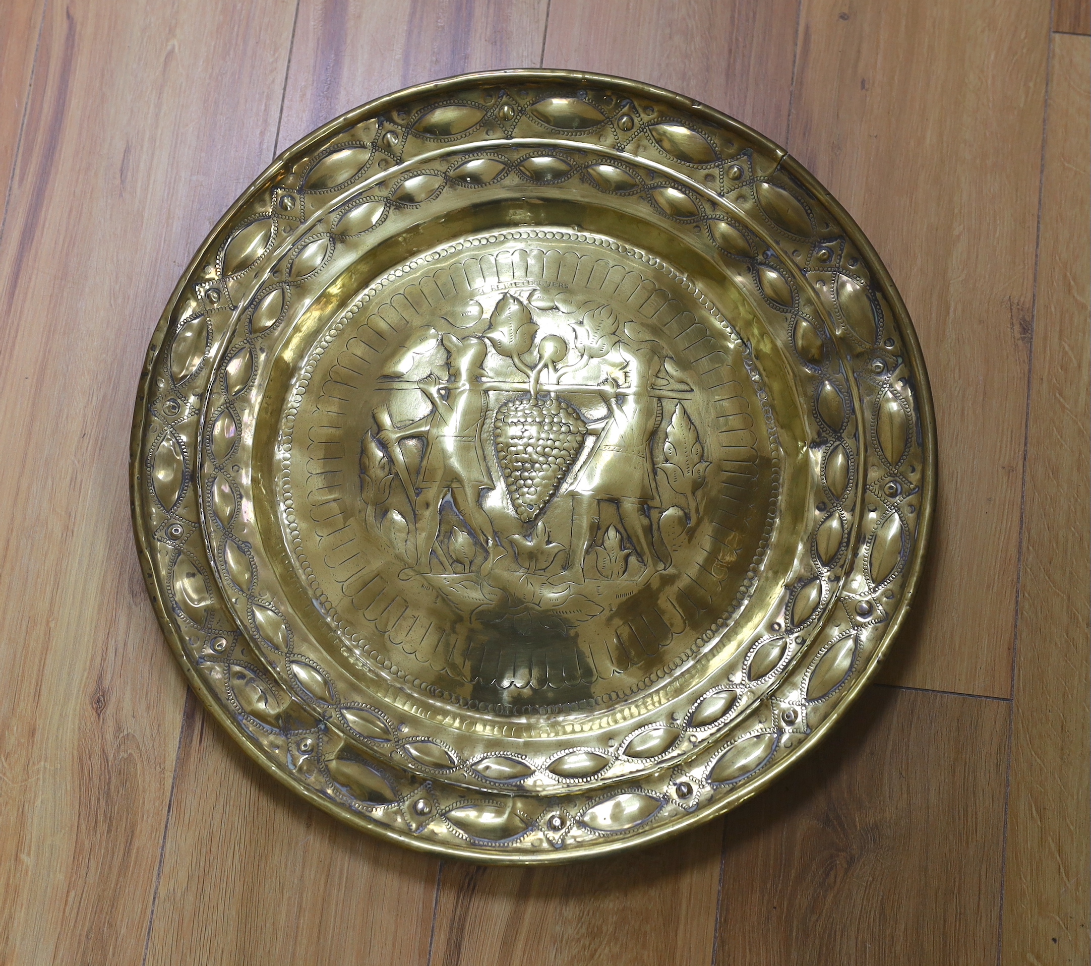 A brass Nuremberg Alms dish embossed with two figures, signed F Reimet Dreyers, 47cm in diameter