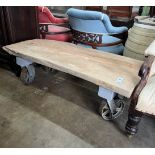 An industrial style rectangular waney edge plank top coffee table on spoked wheel base, width 122cm,