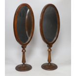 A pair of oval walnut framed shaving mirrors, each 51cm high