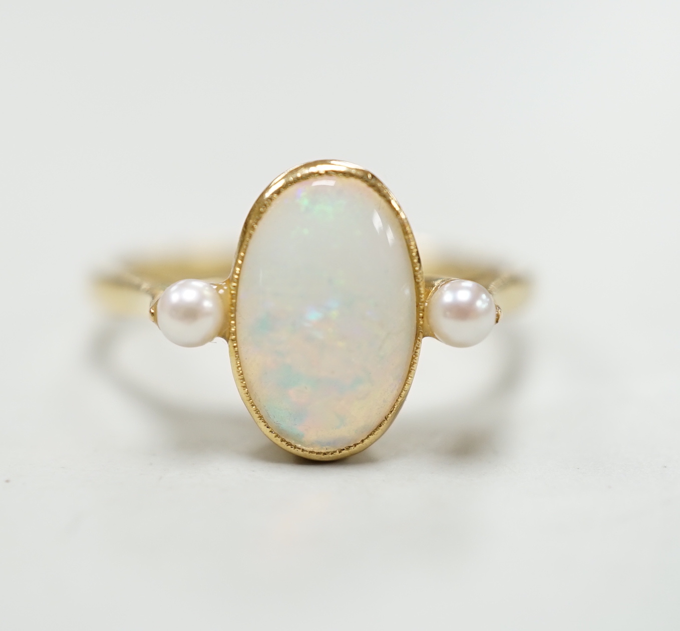 An 18ct, white opal and cultured pearl set three stone ring, size M, gross weight 3.1 grams.