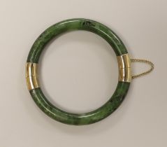 A spinach green jade bangle with metal mounts, 8.5 cm diameter (outer edge to edge)