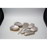 Six assorted silver mounted brushes and a silver mounted hand mirror.