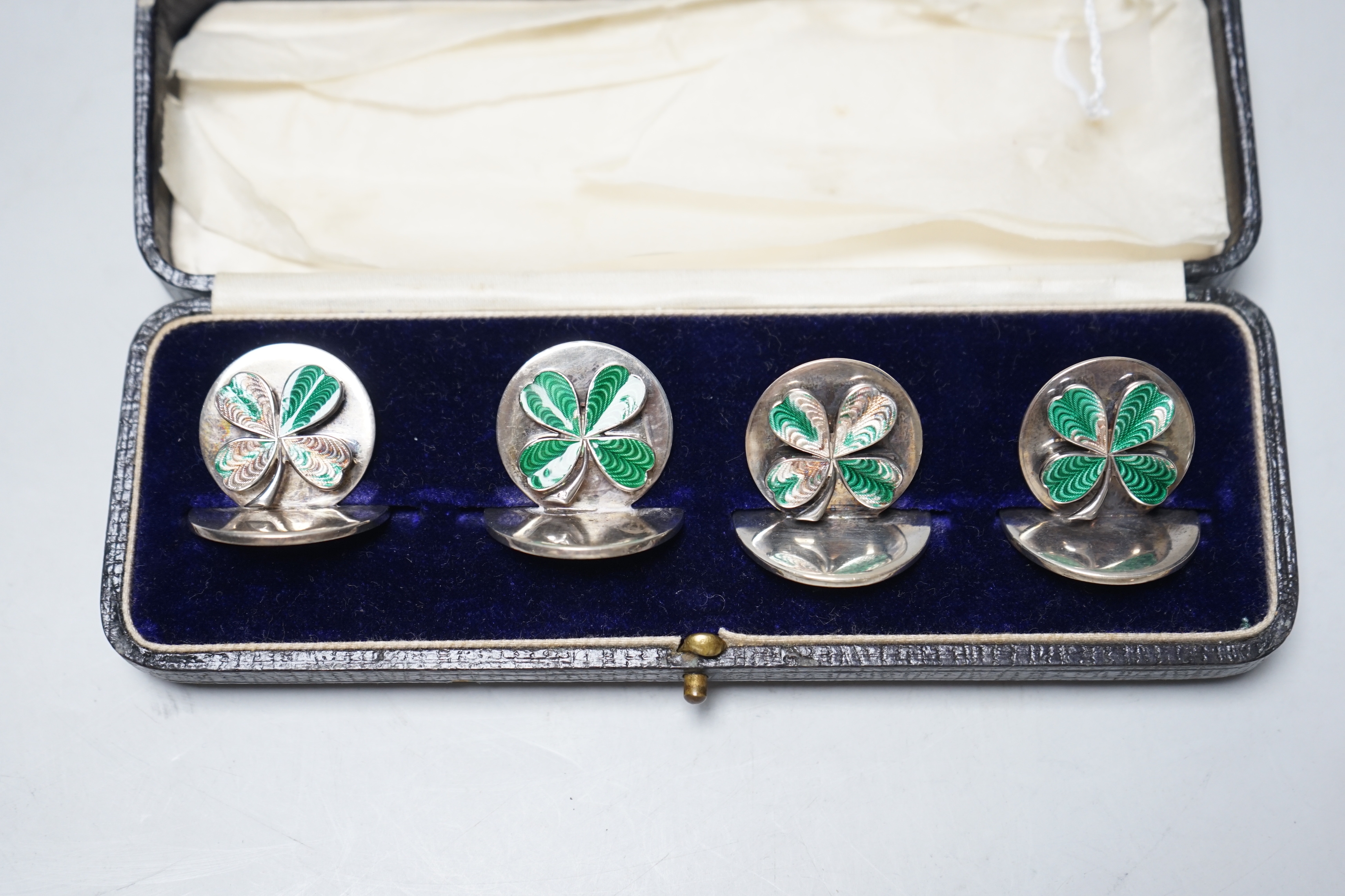 A cased set of four George V enamelled silver menu holders, decorated with four leaf clovers, by - Image 2 of 3