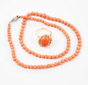 A 1970's 18ct gold and cabochon coral ring, size M, gross weight 6 grams and a coral bead necklace.