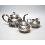 A Chinese white metal three piece tea set, decorated with chrysanthemums, stamped 'Singere', gross