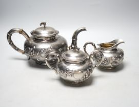 A Chinese white metal three piece tea set, decorated with chrysanthemums, stamped 'Singere', gross