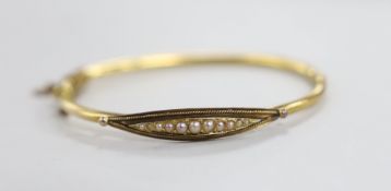 An Edwardian 15ct and graduated seed pearl set hinged bangle, gross weight 7 grams.