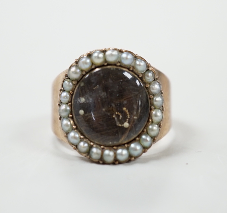 A George III yellow metal mourning ring, with plaited hair beneath a glazed panel and seed pearl set