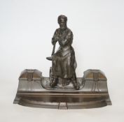 A WMF style spelter ‘Industry’ inkstand, figure with tools and an anvil, hinged ink wells either