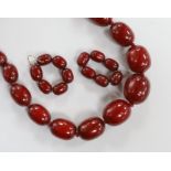 A single strand graduated simulated cherry amber necklace, 64cm and a pair of similar earrings,