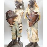 A pair of Continental painted pottery figures of Nubian water carriers, tallest 89cm high