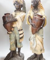A pair of Continental painted pottery figures of Nubian water carriers, tallest 89cm high