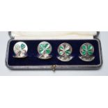 A cased set of four George V enamelled silver menu holders, decorated with four leaf clovers, by