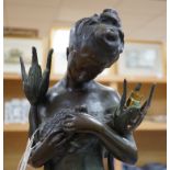 A figural bronze two branch floor standing lamp in the form of a lady holding a bird, indistinct