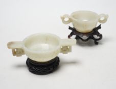 Two Chinese pale celadon jade cups, Qing dynasty, on carved hardwood stands, largest 13cm wide
