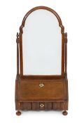 A Queen Anne walnut toilet mirror with arched bevelled plate, fitted interior and serpentine base