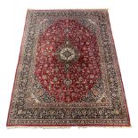 A Kashan burgundy ground carpet, the lobed central floral medallion within a dense floral field