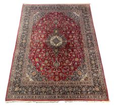 A Kashan burgundy ground carpet, the lobed central floral medallion within a dense floral field