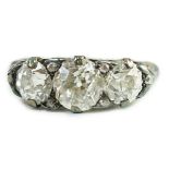 An antique gold, silver and graduated three stone diamond set ring, with diamond chip spacers and