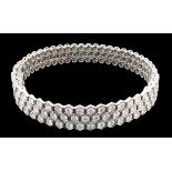 A modern 18ct white gold and diamond cluster set hinged bangle, the diamonds in a hexagonal setting,