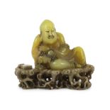 A Chinese soapstone seated group of a luohan and a lion-dog, on a soapstone stand, 18th century, the
