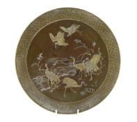 A Japanese Komai style mixed metal inlaid bronze dish, Meiji period, decorated with cranes by a