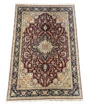 A Tabriz part silk burgundy ground carpet, the central lobed floral medallion within a conforming