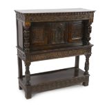 A Charles I carved oak court cupboard with later foliate scroll carving, central arched panel of