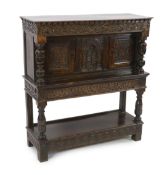 A Charles I carved oak court cupboard with later foliate scroll carving, central arched panel of