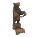 A late 19th century Black Forest carved wood bear stick stand, the bear rearing on two feet, a
