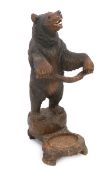 A late 19th century Black Forest carved wood bear stick stand, the bear rearing on two feet, a