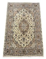 A Kashan ivory ground carpet, the central oval medallion within a dense floral field and wide