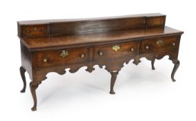 A late 18th century oak dresser base, the raised box back with a drawer to each end over three