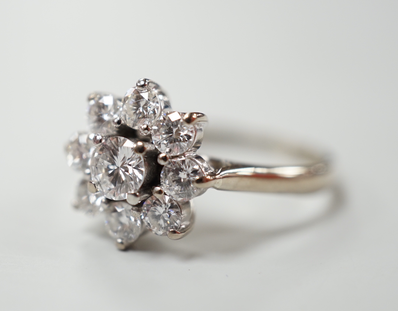 An 18ct, plat. and nine stone diamond set flower head cluster ring, the central stone weighing - Image 2 of 4