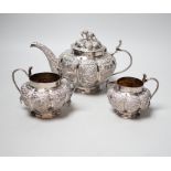 An Indian embossed white metal three piece tea set, with cobra handles and elephant finial, 25.