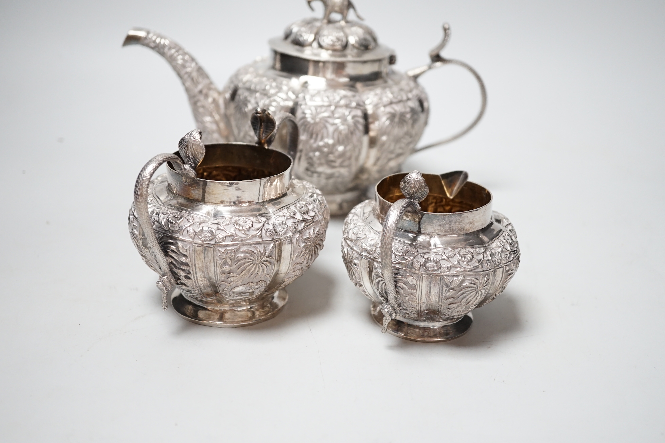 An Indian embossed white metal three piece tea set, with cobra handles and elephant finial, 25. - Image 4 of 5