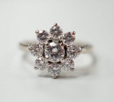 An 18ct, plat. and nine stone diamond set flower head cluster ring, the central stone weighing