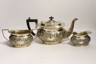 An Edwardian embossed silver three piece tea set, William Devonport, Birmingham, 1909, gross