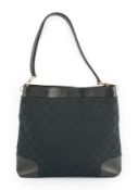 A Gucci black GG canvas shoulder bag with leather trim, leather strap, open top, and interior zip