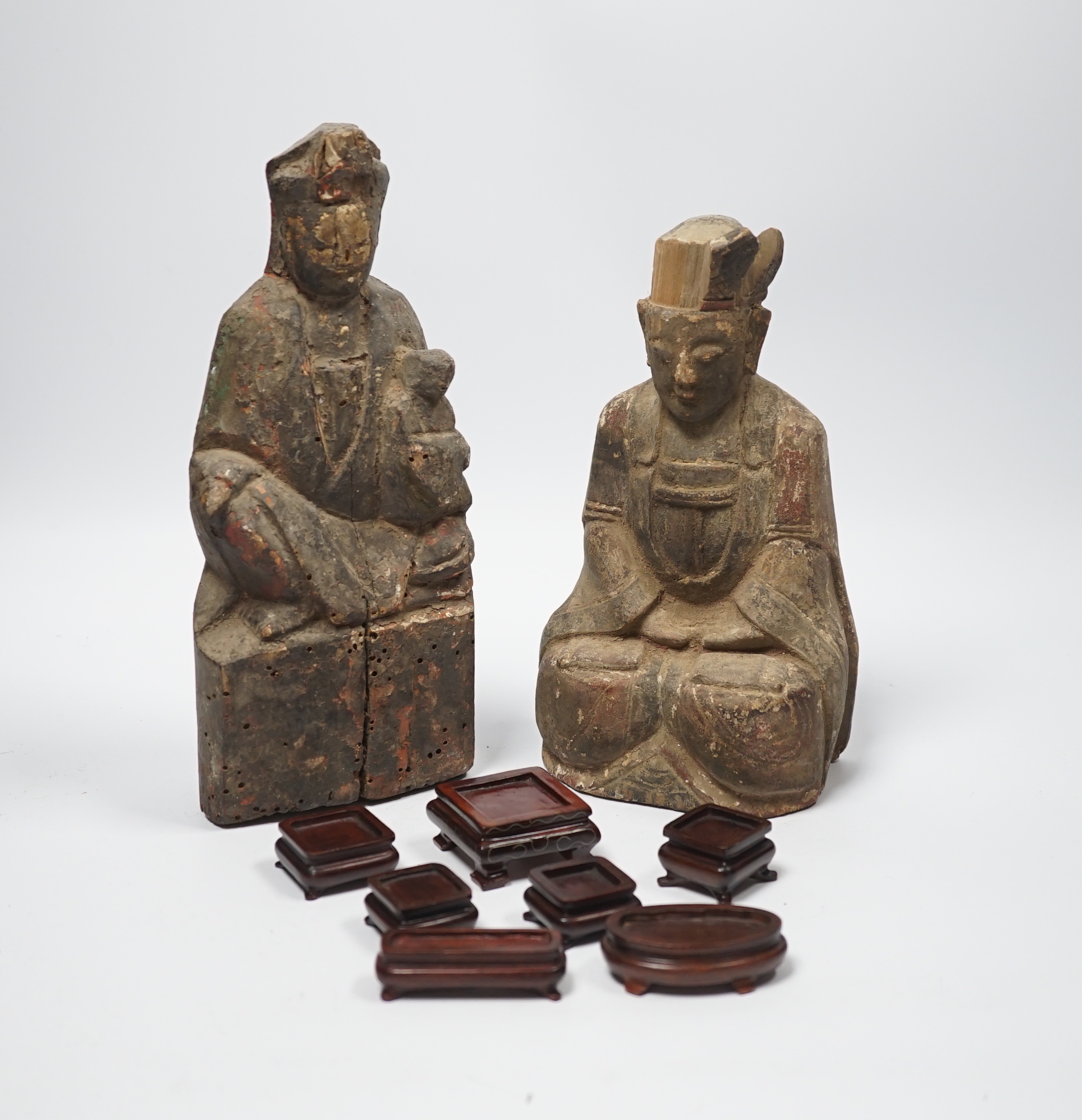 Two Chinese or Southeast Asian carved wood figures of seated immortals, and seven small wood stands,