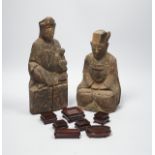 Two Chinese or Southeast Asian carved wood figures of seated immortals, and seven small wood stands,