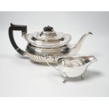 An Edwardian demi fluted silver teapot, London, 1904, together with a later silver sauceboat,