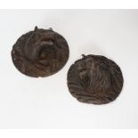 A pair of German Black Forest carved plaques of wild dogs, largest 18cm diameter