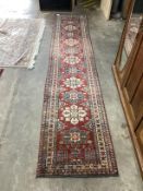 A Caucasian style red ground runner, 390 x 80cm