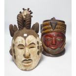 An Igbo maiden spirit mask and an African tribal helmet mask, largest 46cm wide