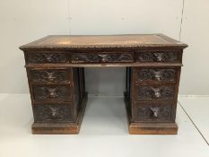 A late Victorian carved oak pedestal desk with lion mask cup handles, width 122cm, depth 70cm,