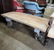 An industrial style rectangular waney edge plank top coffee table on spoked wheel base, width 122cm,