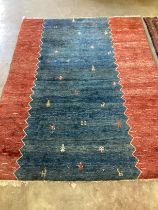 A Gabbeh blue ground carpet woven with figures and animals, 276cm x 208cm