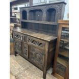 A 17th century style “Tudor Furniture” carved oak dresser, width 146cm, depth 53cm, height 168cm