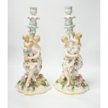 A pair of German floral encrusted porcelain candlesticks of a mother and child group, 38cm high